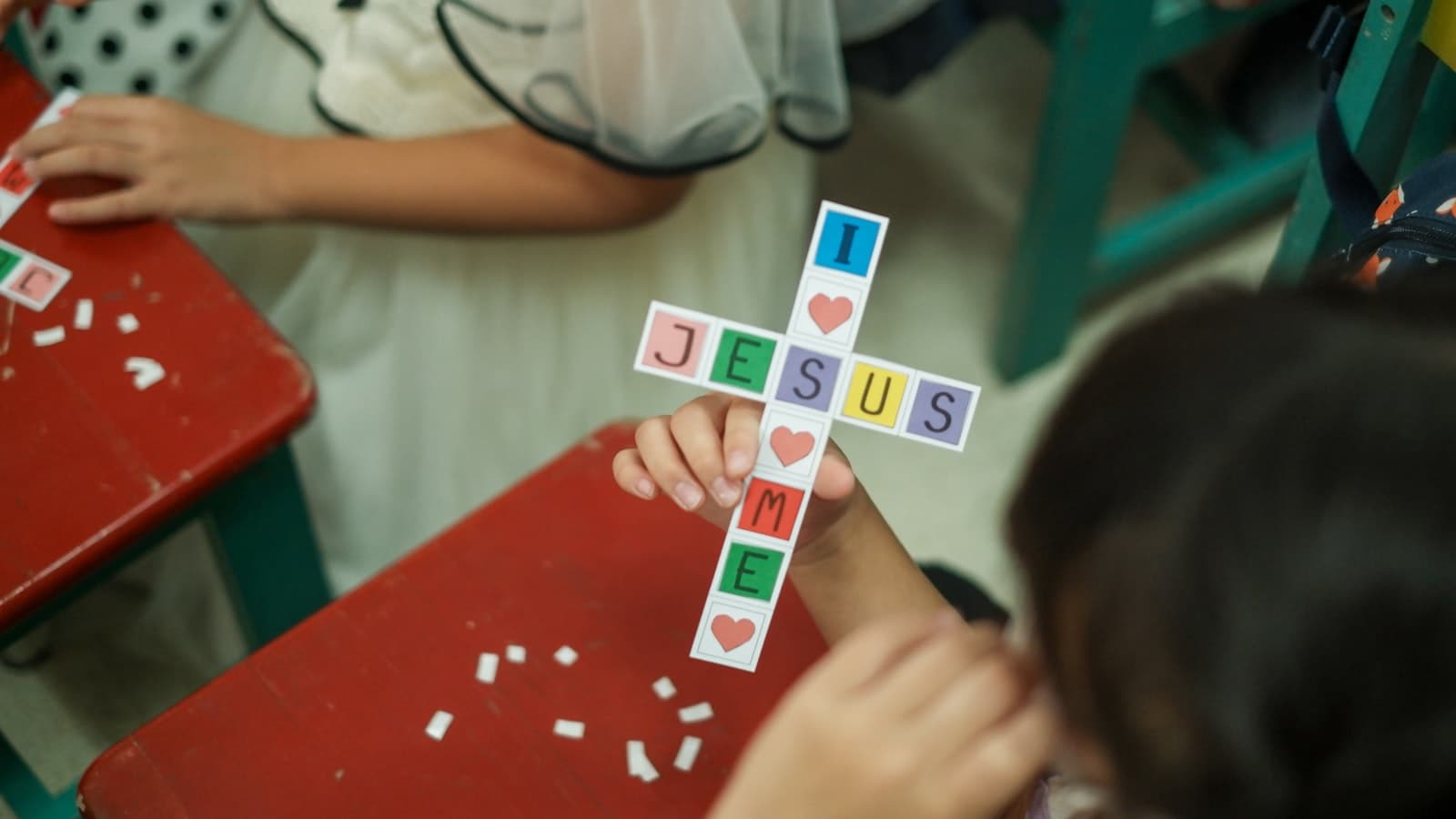 A child holding a paper cross craft in a Sunday school class