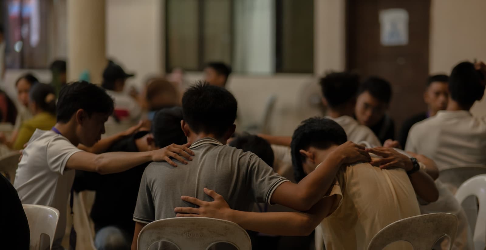 Young men praying together with hands on each other's shoulders